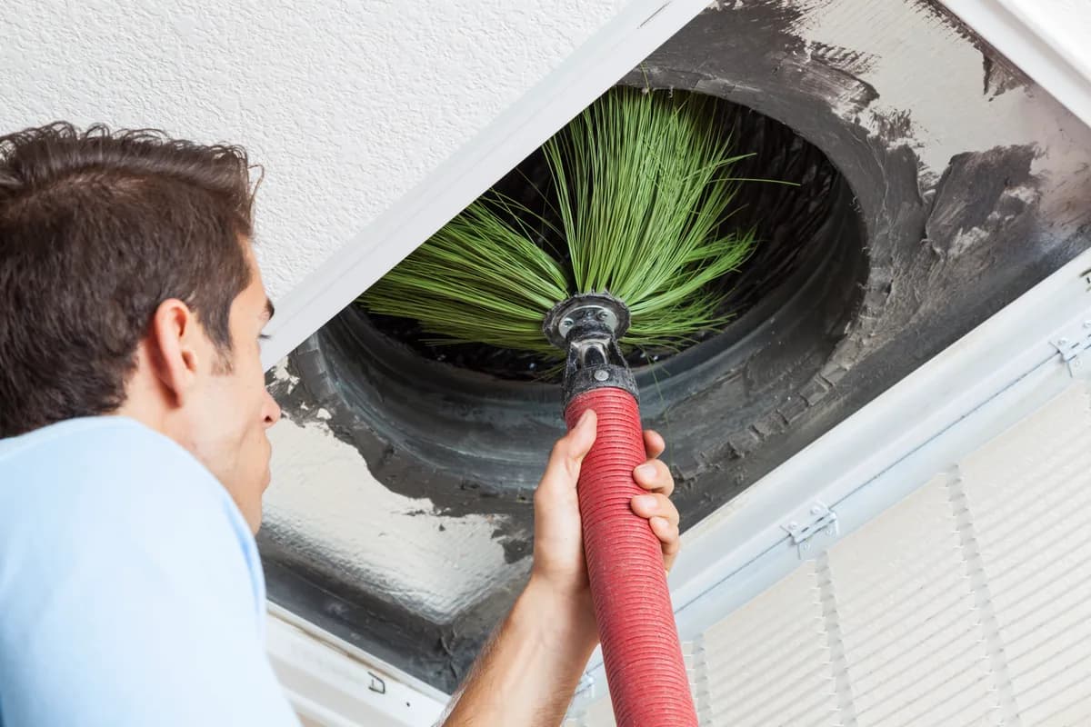 Technician vacuuming dust and debris from a residential air duct