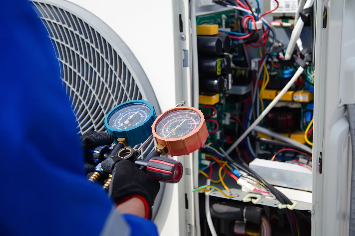 HVAC technician testing a capacitor inside an air conditioner condenser at a GTA home