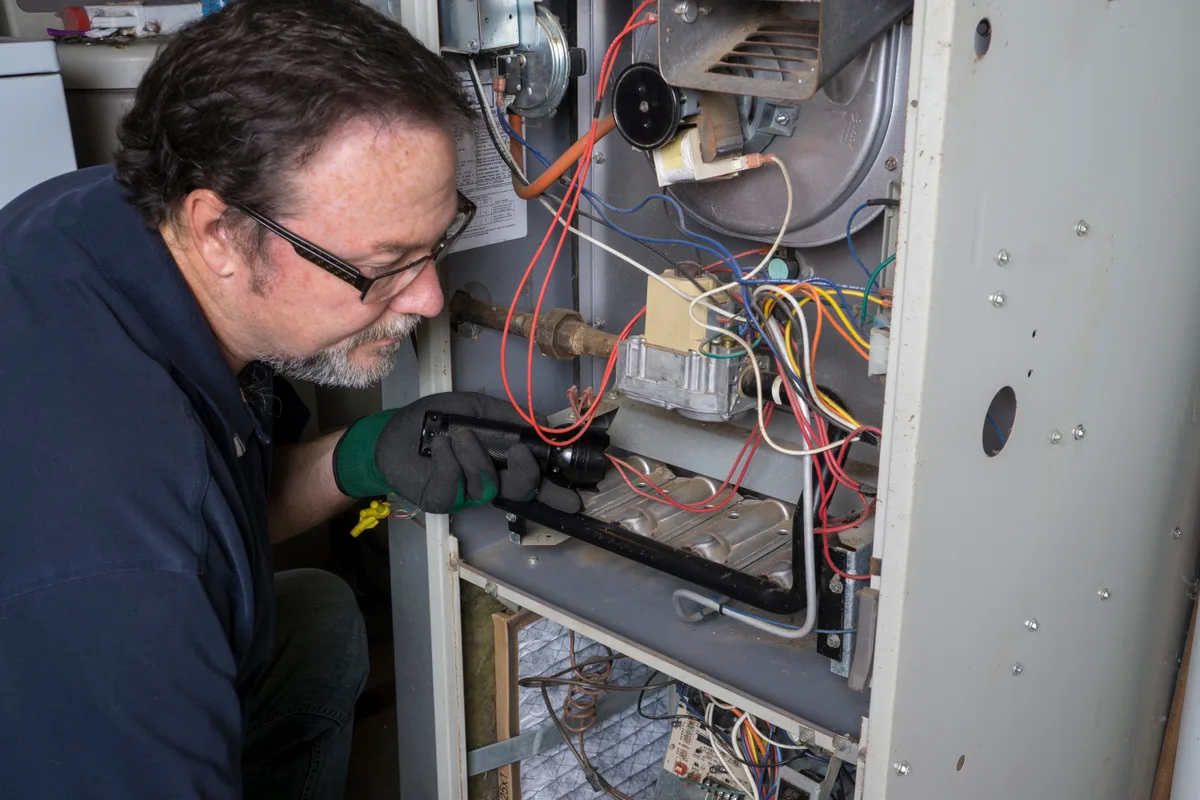 HVAC technician repairing a gas furnace in a Toronto home with diagnostic tools