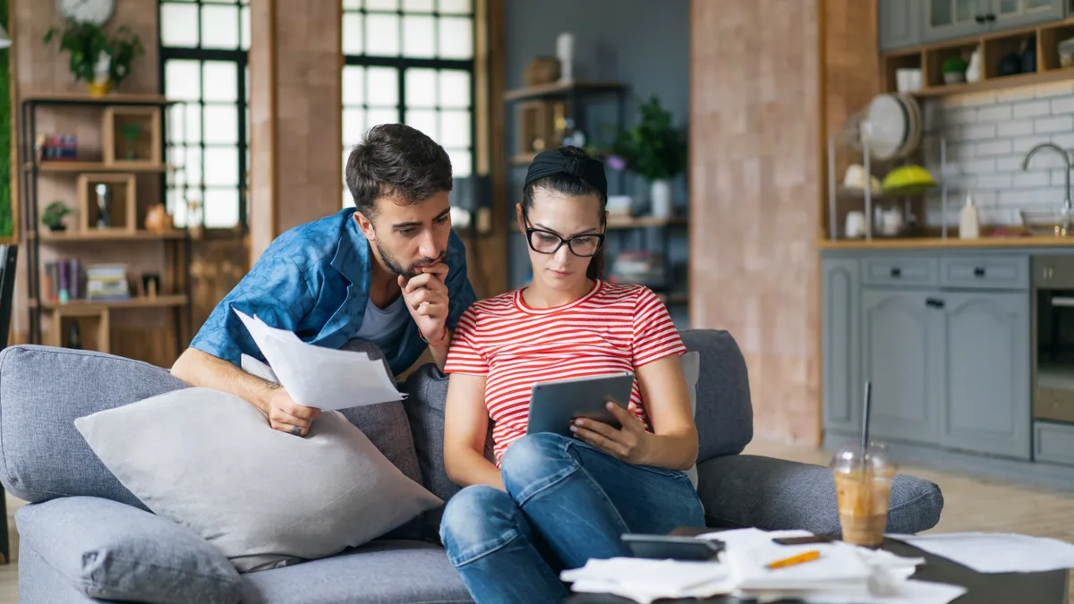 Couple calculating HVAC financing payments with a calculator and tablet at home