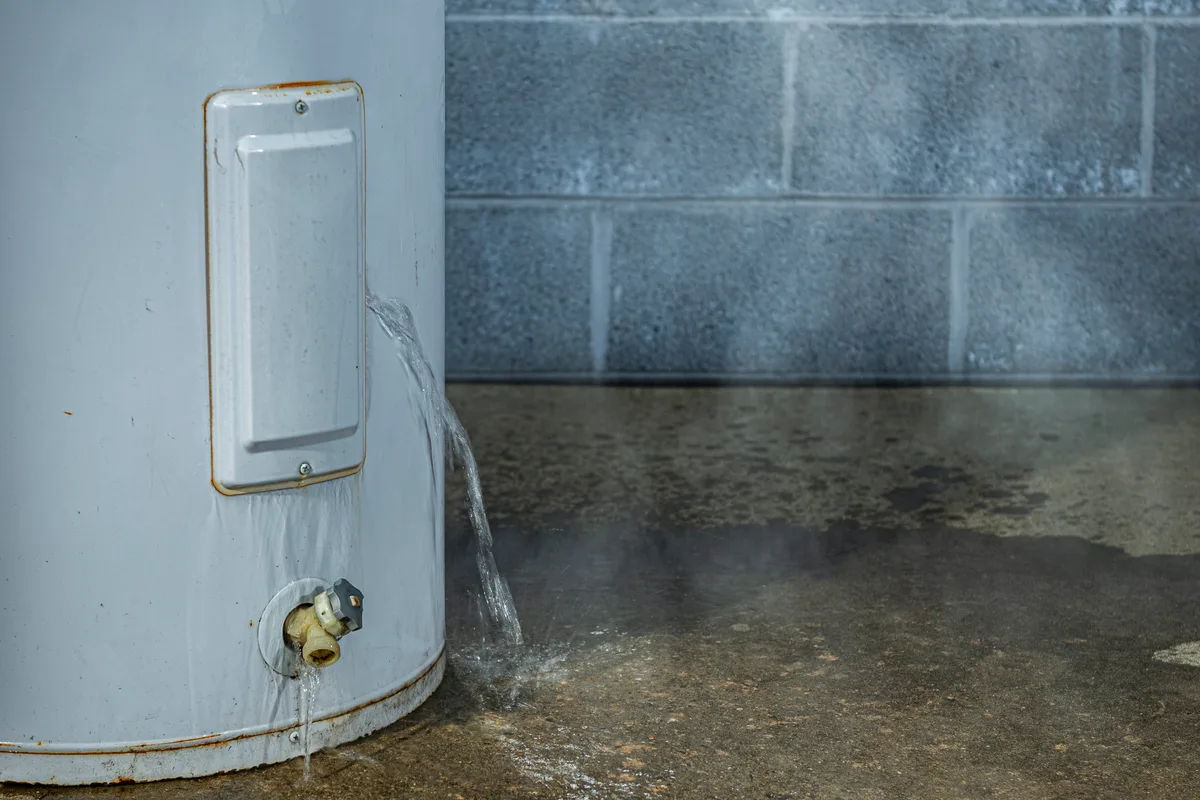 Water pooling on a basement floor beneath a leaking tank water heater