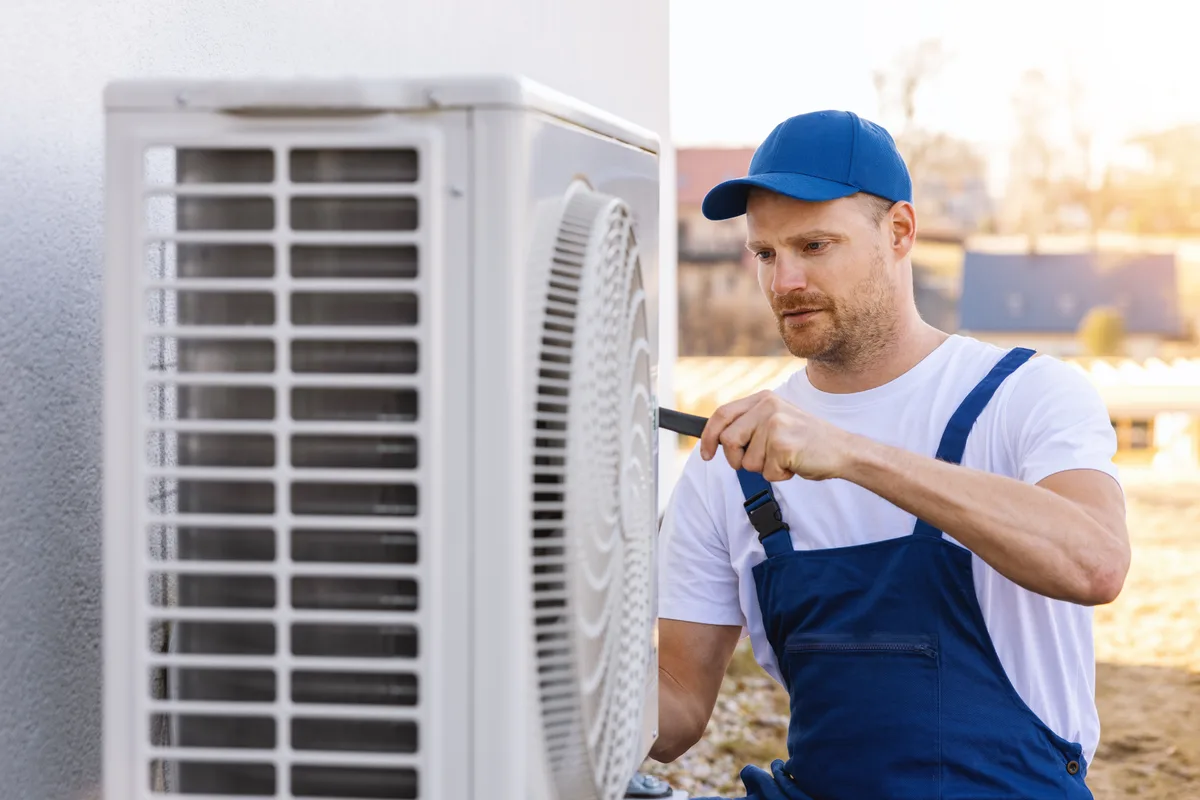 HVAC technician installing a new outdoor air conditioner unit during a system replacement