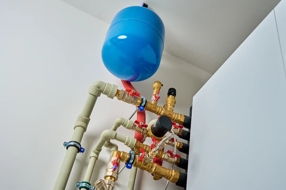 Small thermal expansion tank mounted on the cold water supply line above a residential water heater