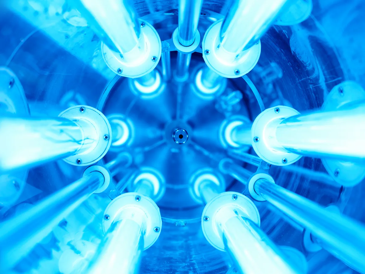 Germicidal UV-C lamp glowing blue inside a furnace plenum above the evaporator coil