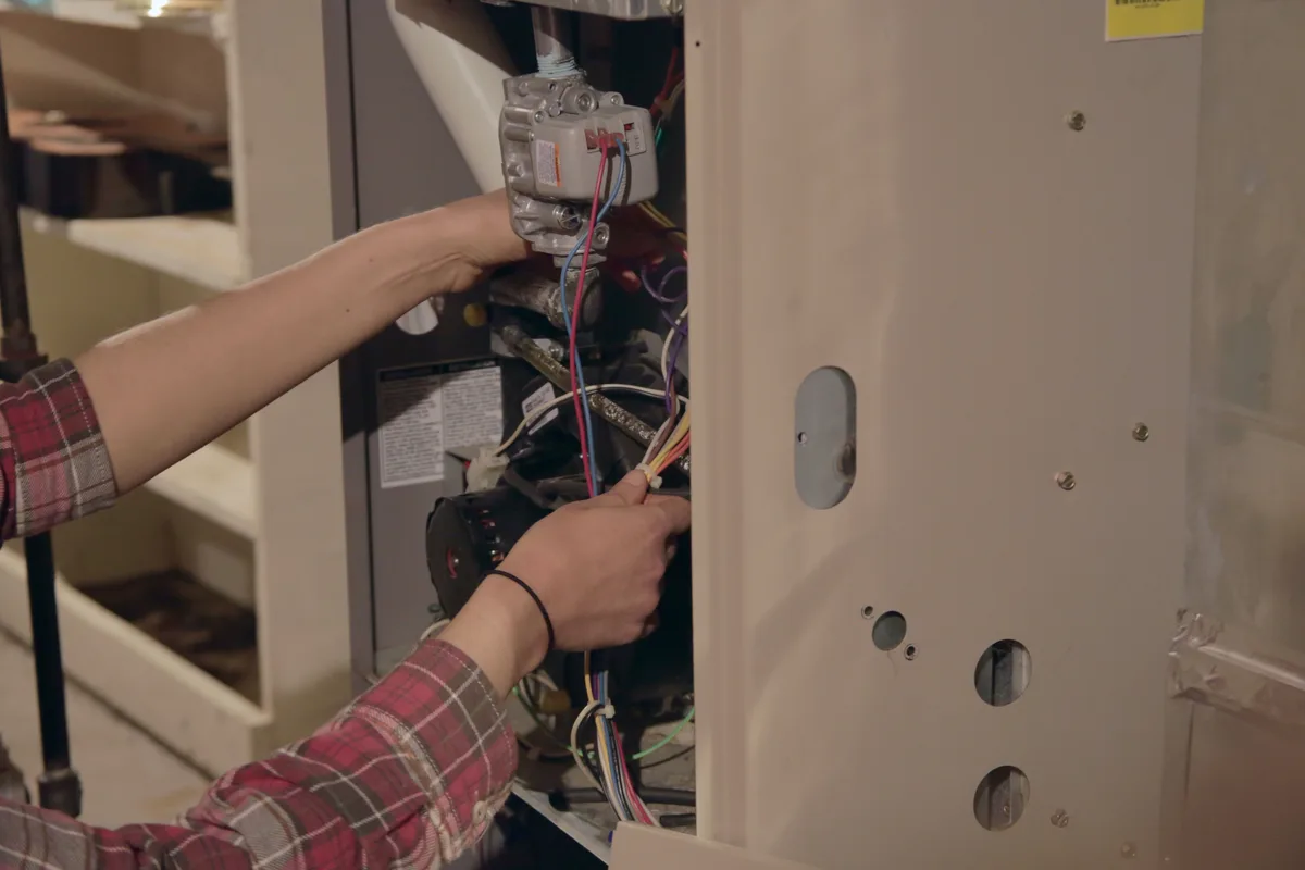 Technician's hands servicing burner components during a furnace tune-up