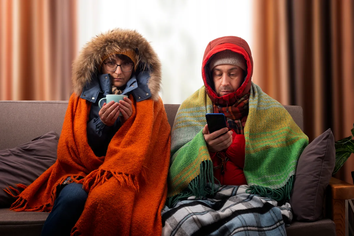 Family bundled in winter coats inside a cold living room after the furnace stopped working
