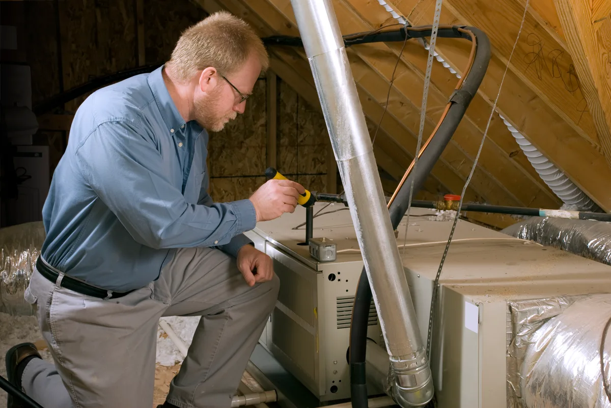 Technician inspecting a furnace blower motor while diagnosing a noisy heating system