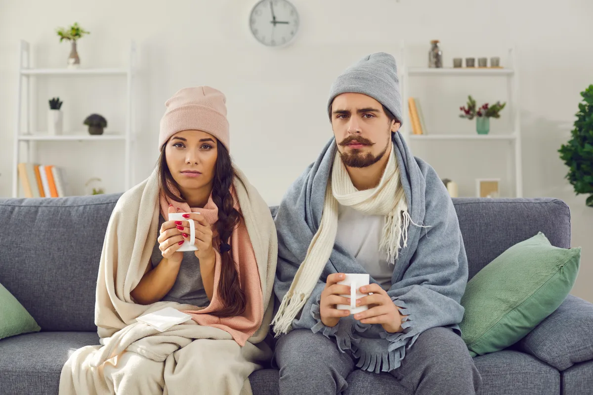 Couple bundled up in a cold room of their home due to uneven heating