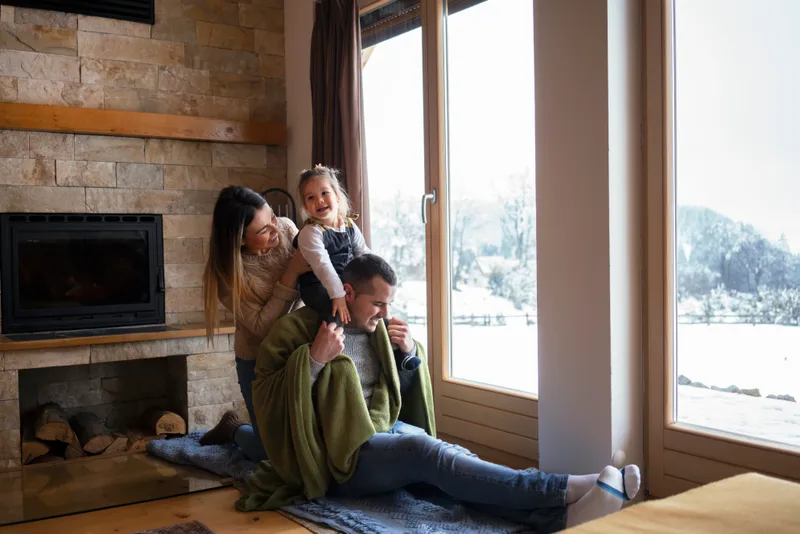Family together by a bright window on a snowy day