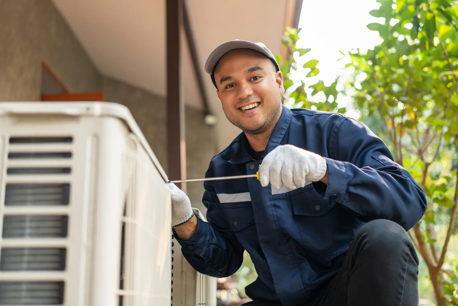 HVAC technician servicing an outdoor air conditioning unit at a home