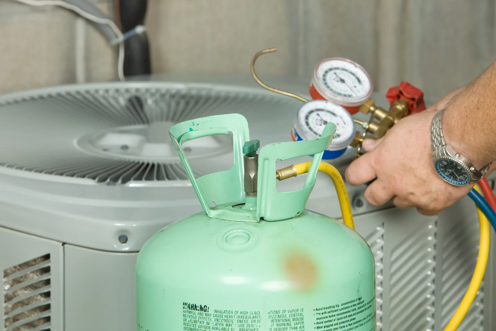 Technician checking air conditioner refrigerant with manifold gauges