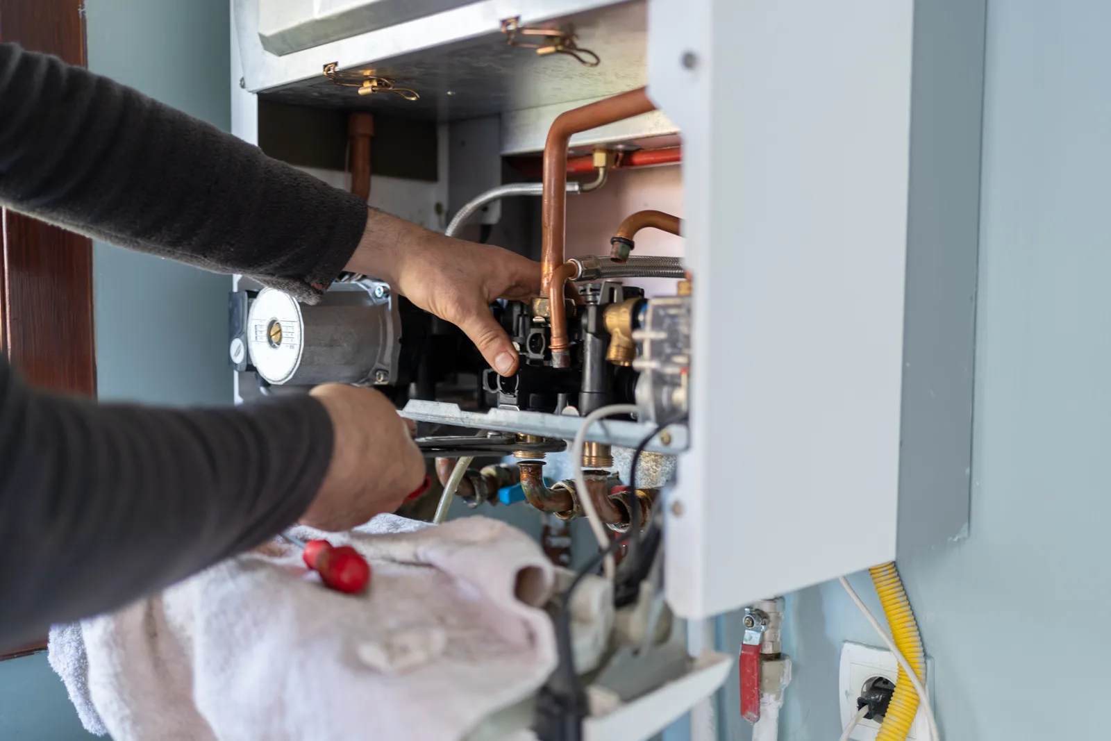 Technician servicing the internal components of a residential boiler