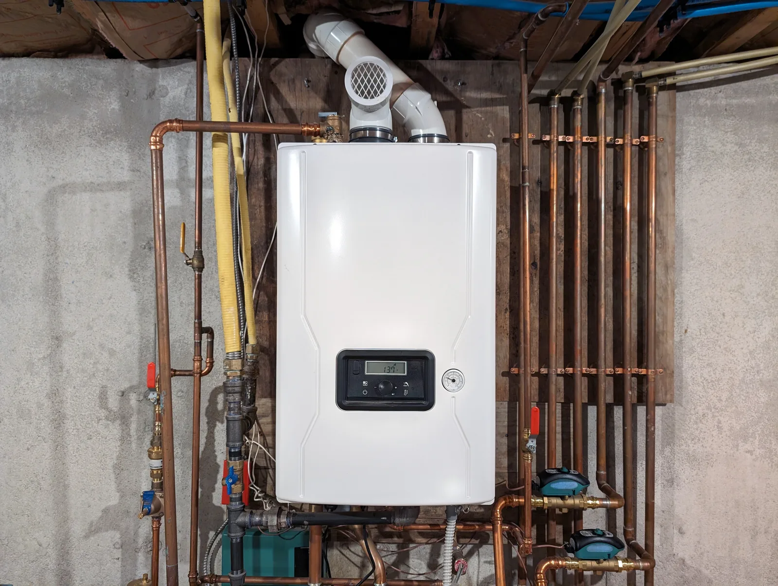 Wall-mounted gas tankless water heater with copper piping in a basement