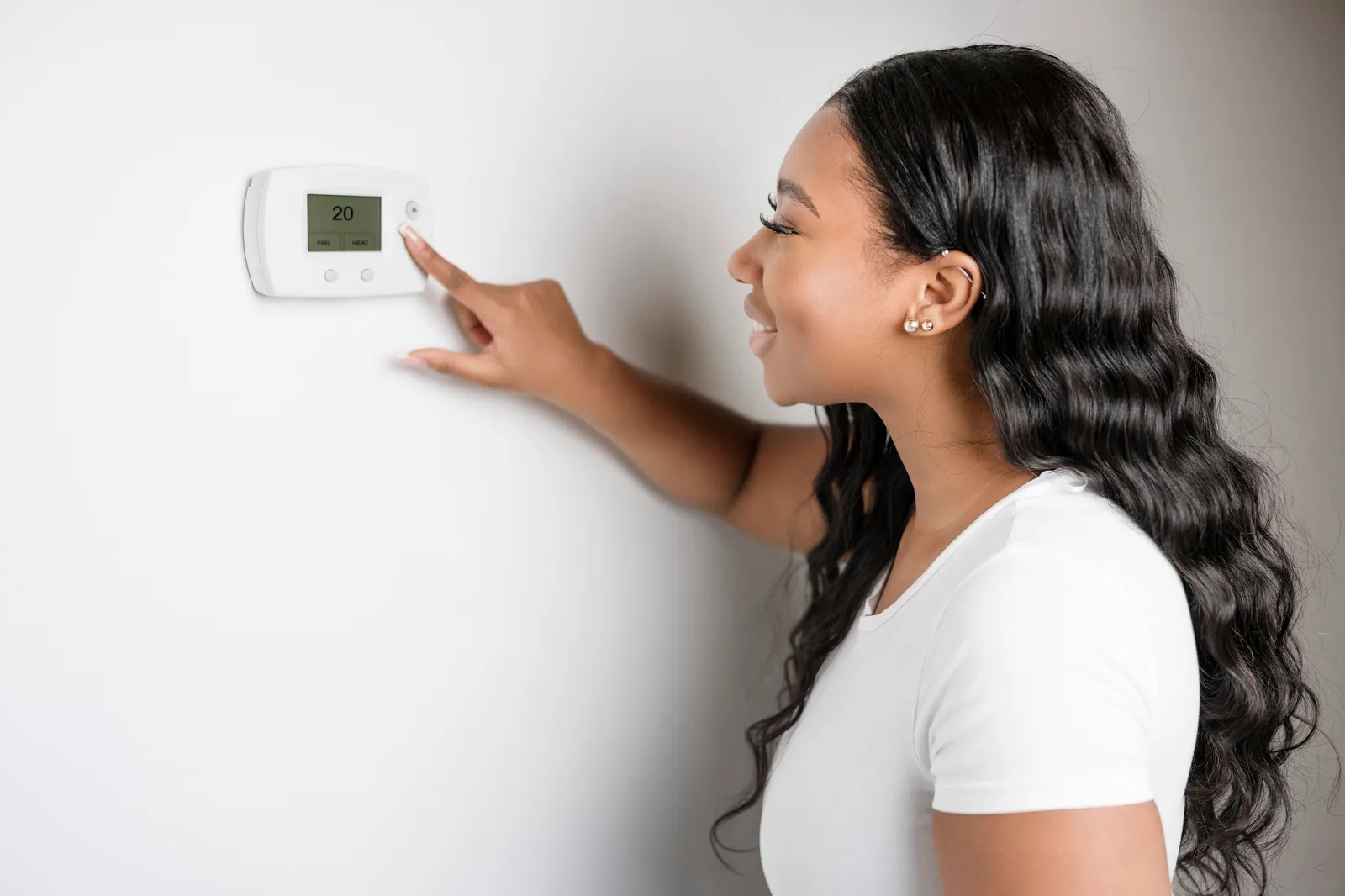 African woman lady adjusting the climate control panel on the wall