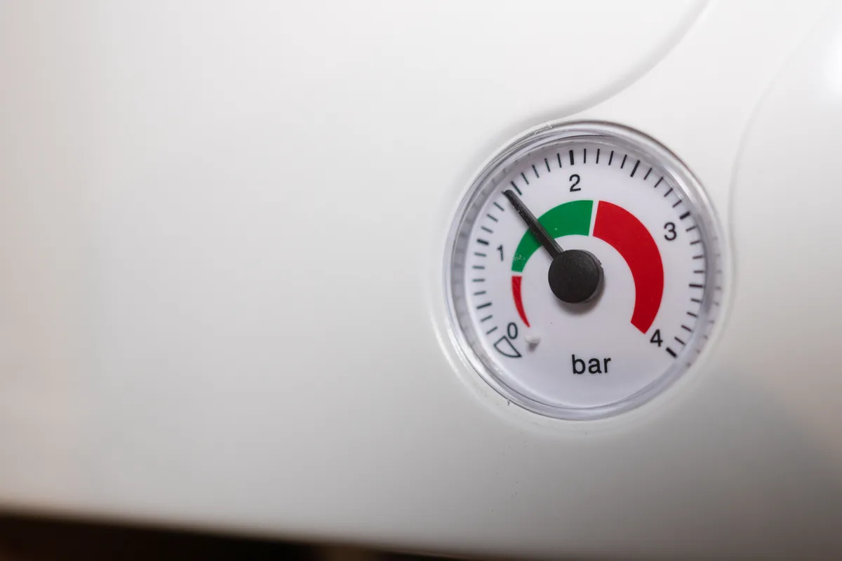 Hand pointing to the temperature dial on a gas water heater