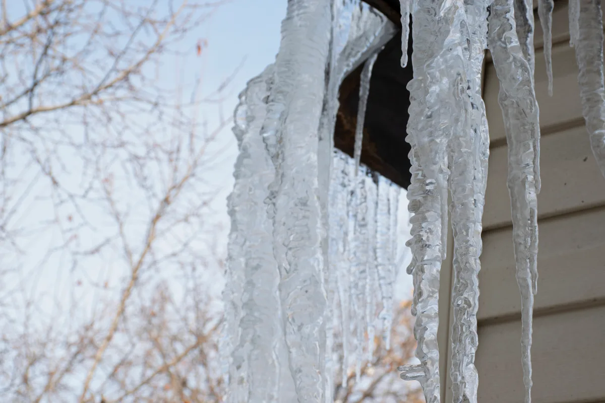 Large icicles hanging from the roof of a residential building