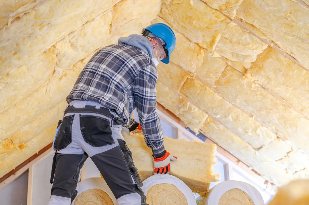 Worker installing insulation in a residential attic