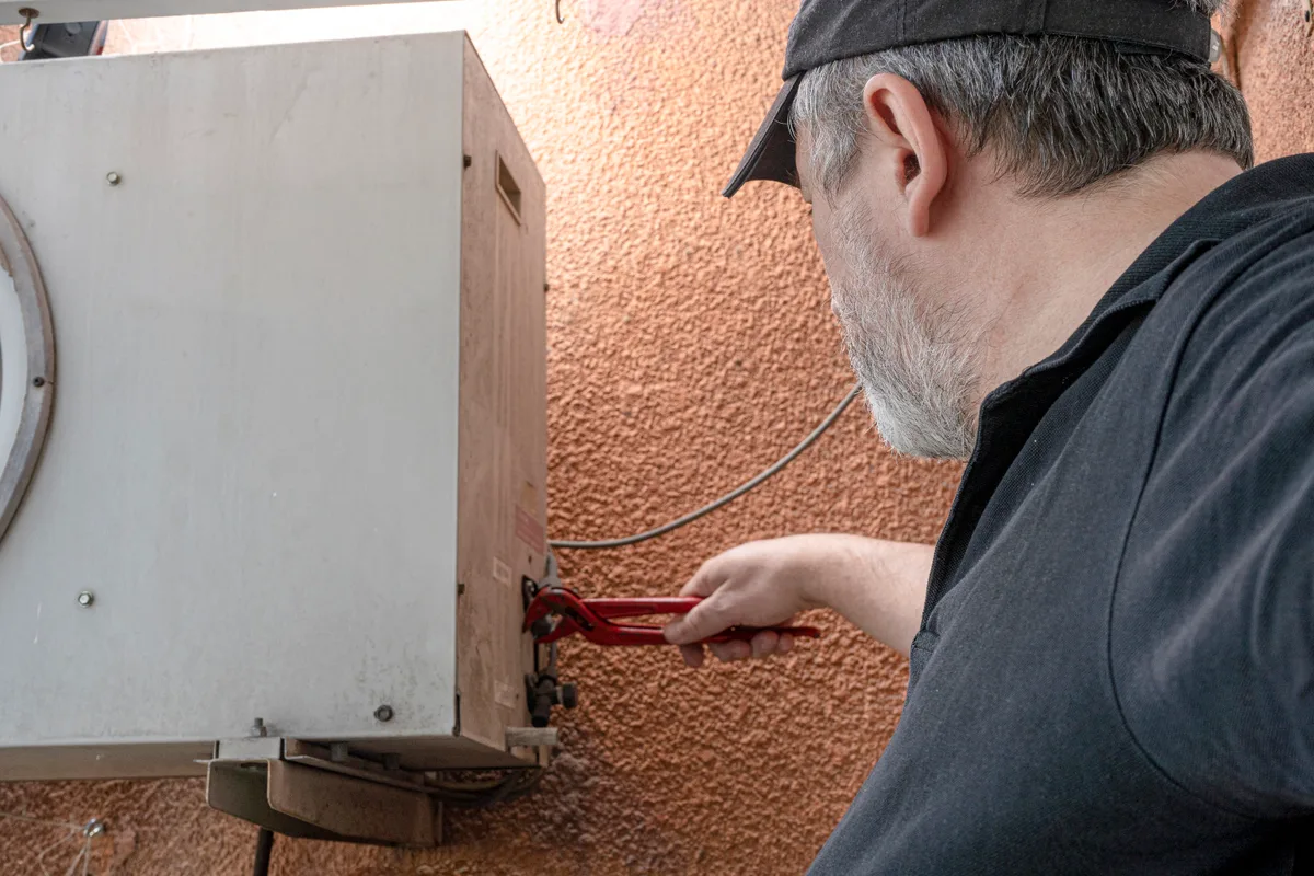 Technician adjusting the refrigerant connections on an outdoor AC unit