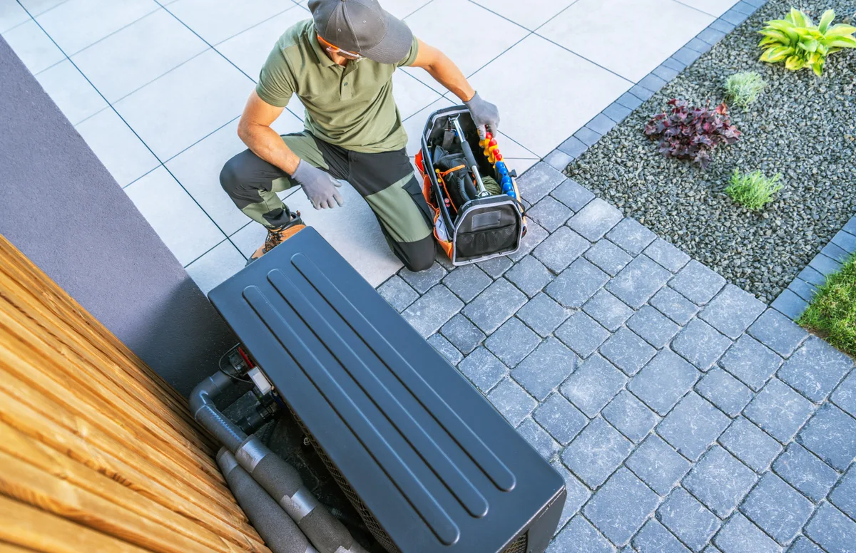 Technician working on an outdoor HVAC unit in a residential area
